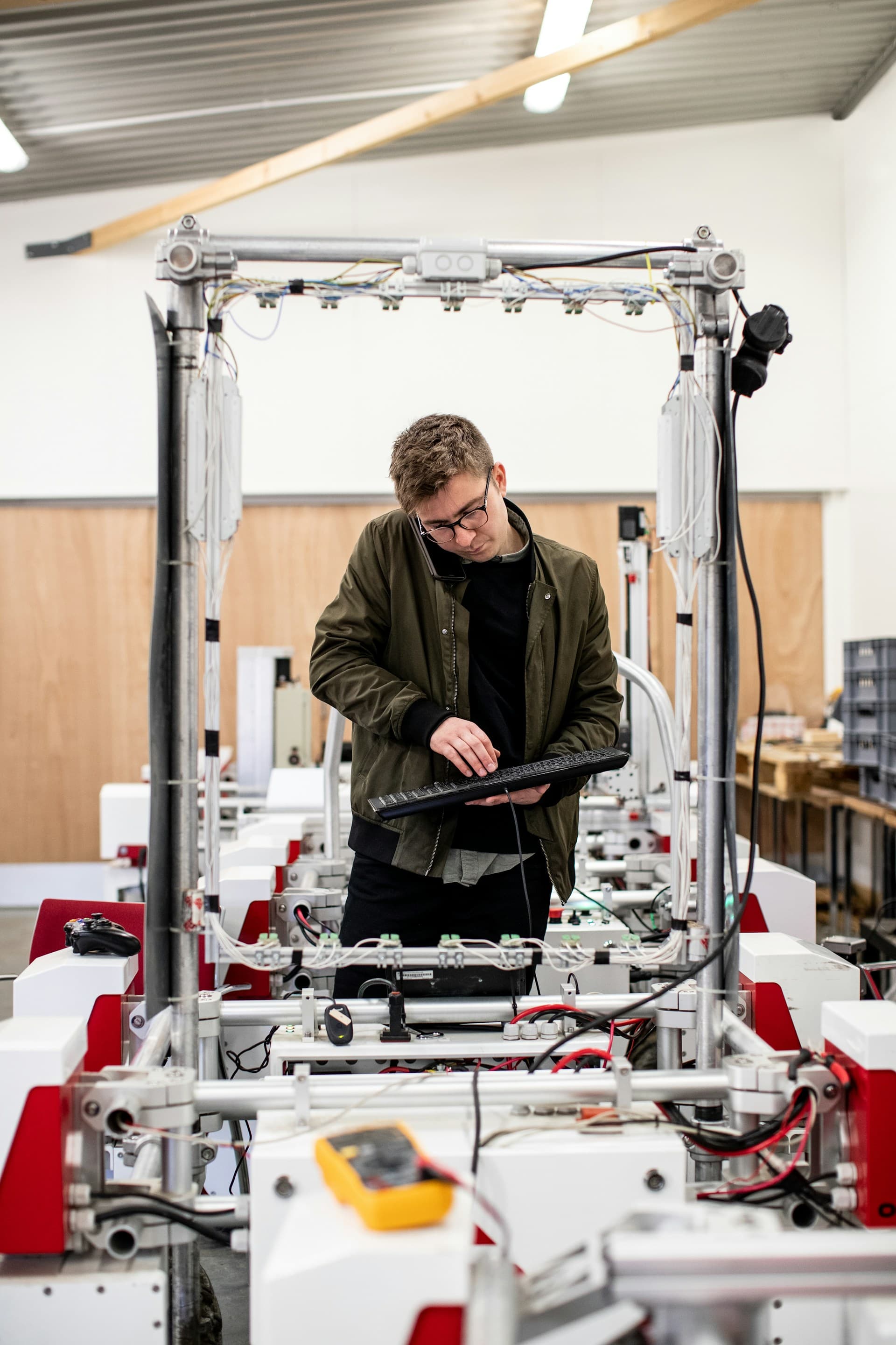 Ein Techniker prüft eine automatisierte Fertigungsanlage mit einem Messgerät, sinnbildlich für einen Zulieferbetrieb aus Industrie und Produktion.